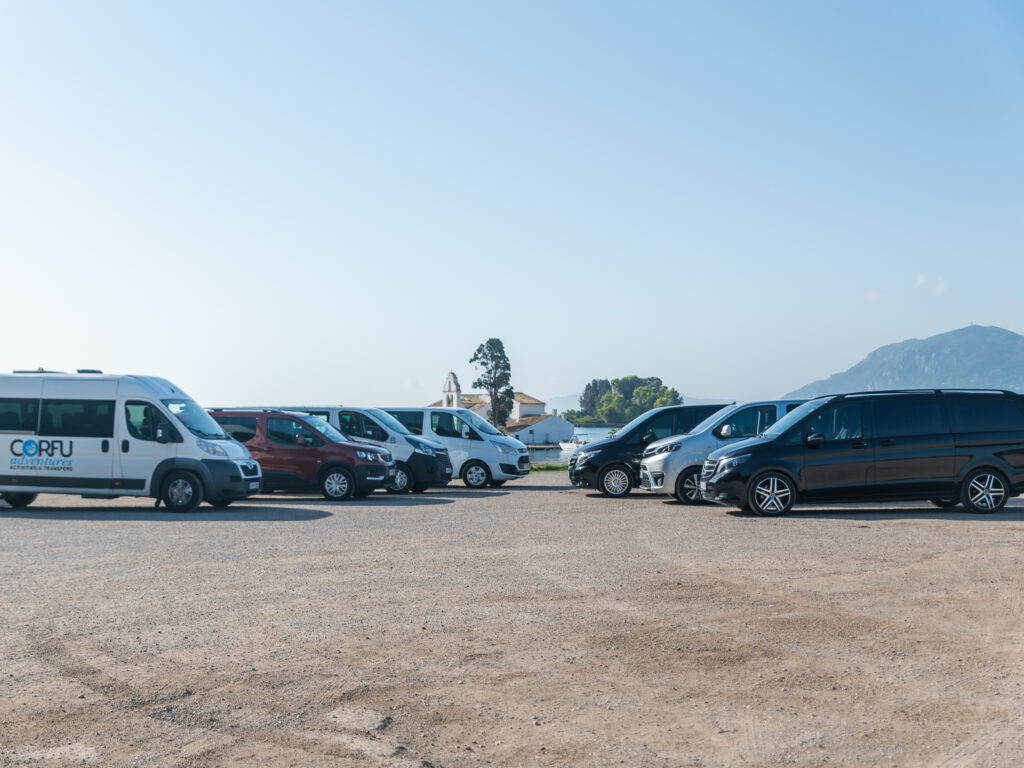 Corfu Adventures transfer fleet of minibuses and vans parked by the sea near Kanoni, Corfu